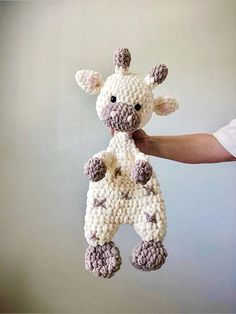 a crocheted giraffe is being held up by someone's hand