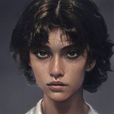 a close up of a person wearing a white shirt and black hair with freckled bangs