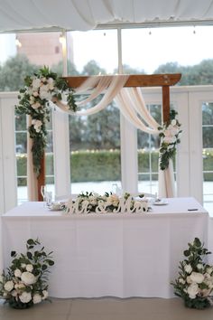 the table is set up with white flowers and greenery for an elegant wedding reception