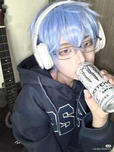 a person with blue hair and headphones drinking from a can