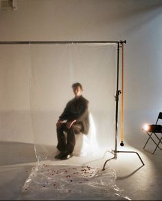 a man sitting on a chair in front of a white backdrop with red sprinkles