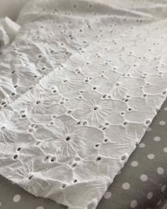 a close up of an unmade bed with white sheets and polka dots on it