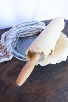 two burritos sitting on top of a wooden table next to a glass plate