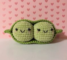 two crocheted peas with their eyes closed sitting next to each other