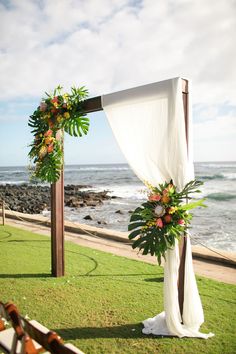 an outdoor wedding setup with flowers and greenery on the grass by the ocean side