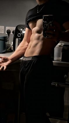 a shirtless man taking a selfie in the kitchen