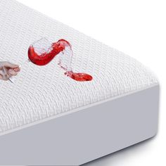 a person's hand reaching for the bottom of a mattress with red paint on it