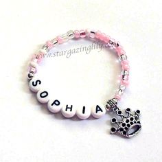 a pink beaded bracelet with the word sophiia and a silver crown charm