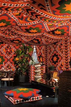 the interior of a tent with colorful patterns on the walls and floor, including an ottoman