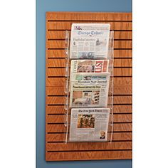 three newspaper racks mounted on a wooden wall