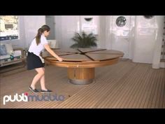 a woman holding a tennis racquet on top of a wooden table in a living room