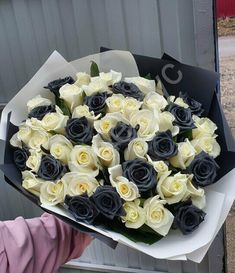 a person holding a bouquet of white and black roses