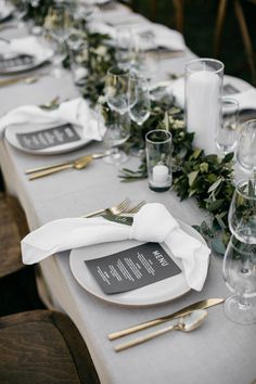 the table is set with place settings, silverware and greenery for an elegant look