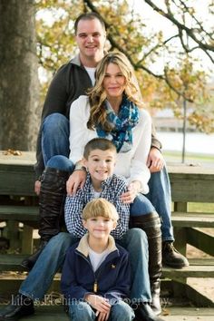 a family sitting on a bench in front of a tree with their arms around each other