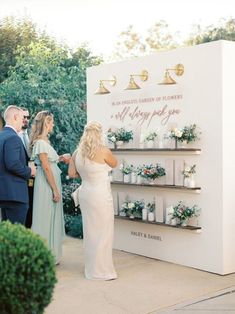 a man and woman are standing in front of a sign with candles on it that says, the garden of flowers is always good for you