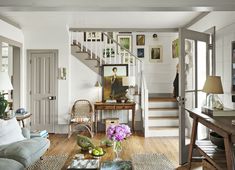 a living room filled with furniture and a stair case in front of a doorway leading to a second floor