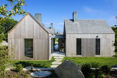 the house is made out of wood and has stone walkways leading to two large windows