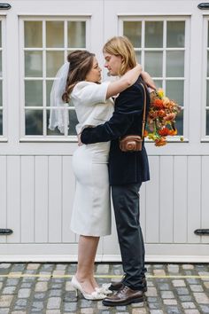 a bride and groom embracing each other in front of a white building