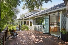 a deck with chairs and potted plants next to a house on the water's edge