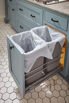 a kitchen with blue cabinets and white counter tops has two bins in the middle