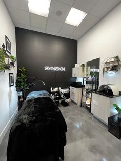 a room with black and white furniture and plants on the wall, along with a large sign that says synson