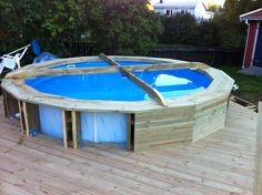 an above ground swimming pool is being built on a deck in a backyard with wooden boards around it