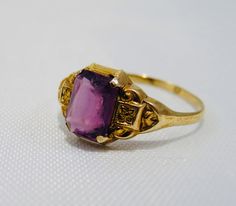 The past will always return in the fashion world and this piece is back for round two! In the 1920's ladies of class wore the most opulent dresses with jewelry to match. As the years continued, jewelry makers tailored pieces to fashion and trends which resulted in affordability for style. Presenting this Beautiful Vintage 10k Gold Old Mine Cushion Cut Amethyst Solitaire Ring Featuring Elegant Victorian Inspired Designs. Approximate Size: Ring Size 6 and 1.1 grams total weight. Stone measures 8mm Art Deco Purple Amethyst Ring For Formal Occasions, Purple Amethyst Art Deco Ring For Formal Occasions, Formal Art Deco Purple Amethyst Ring, Vintage Yellow Gold Hallmarked Amethyst Ring, Art Deco Yellow Gold Amethyst Ring For Formal Occasions, Vintage Yellow Gold Amethyst Ring, Purple Amethyst Art Deco Ring, Vintage Gold Amethyst Rings, Antique Amethyst Gemstone Ring For Formal Occasions