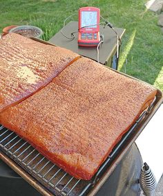 a large piece of meat cooking on top of a grill with a cell phone next to it