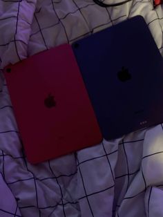 three apple laptops are laying on a bed