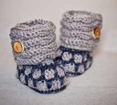 two crocheted baby booties with buttons on the front and bottom are shown