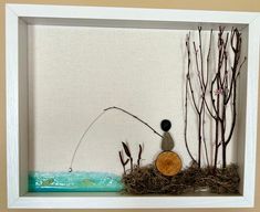 a shadow frame with some plants and a rock in the middle, on a wall