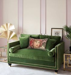 a green couch with a pillow on top of it next to a side table and potted plant