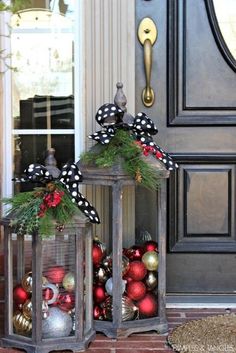 two lanterns decorated with christmas ornaments sit on the front porch