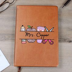 a brown leather notebook with the words mrs copper on it next to a pair of glasses