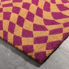 a purple and yellow area rug on the floor with grey floors in front of it