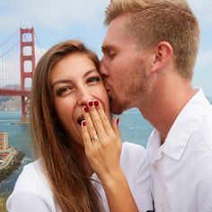 a man and woman kissing in front of the golden gate bridge