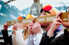 a group of people standing next to each other holding up signs that say downhill from here