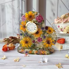 a clock sitting on top of a table next to flowers