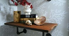 a shelf with books and a skull on it in front of a wallpapered background