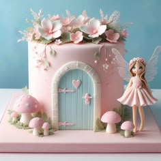 a pink cake with a fairy figurine standing in front of it and flowers on top