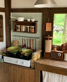 pots and pans are sitting on the stove top in this rustic kitchen with green tile