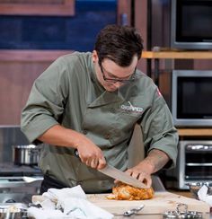 a man cutting food on top of a wooden cutting board