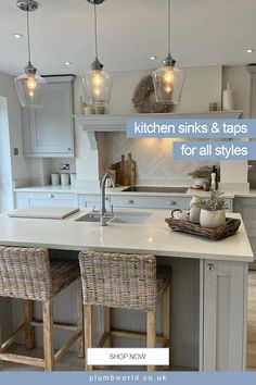 a kitchen with two stools next to an island and some lights above the sink