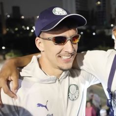 two men in sunglasses and hats are posing for the camera with their arms around each other