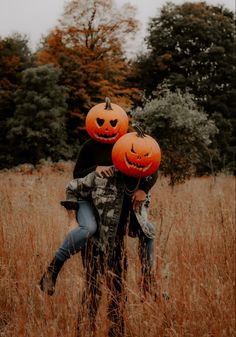 two people hugging each other in a field with pumpkins on their heads and faces