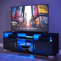 a flat screen tv sitting on top of a black entertainment center next to a purple wall