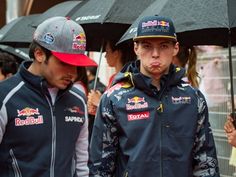 two men standing under umbrellas in the rain with hats on their heads and one man holding an umbrella