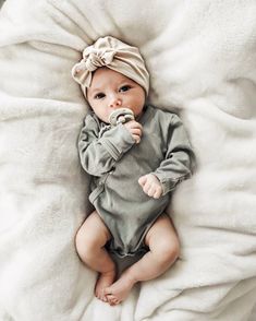 a baby laying on top of a white blanket