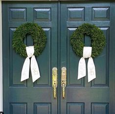 two wreaths are on the front door of a house