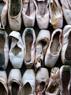 several pairs of ballet shoes lined up against each other